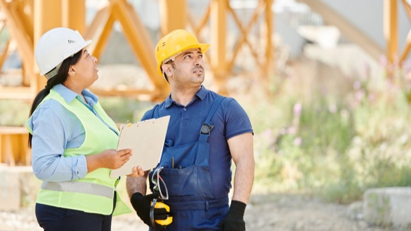 Zwei Handwerker besprechen gemeinsam die Baupläne
