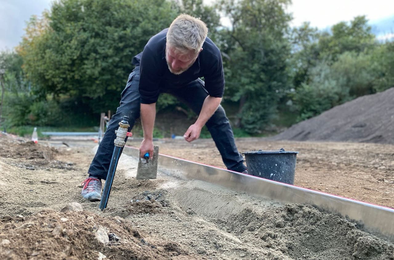 Landschaftsgärtner zieht eine Betonkante auf der Baustelle ab