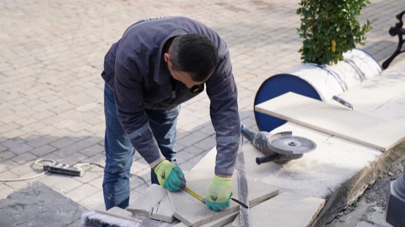 Fachkraft verlegt Platten für eine Terrasse im Garten