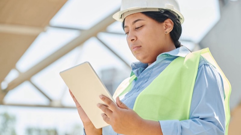 Technikerin erfasst Daten auf der Baustelle mit dem Tablet