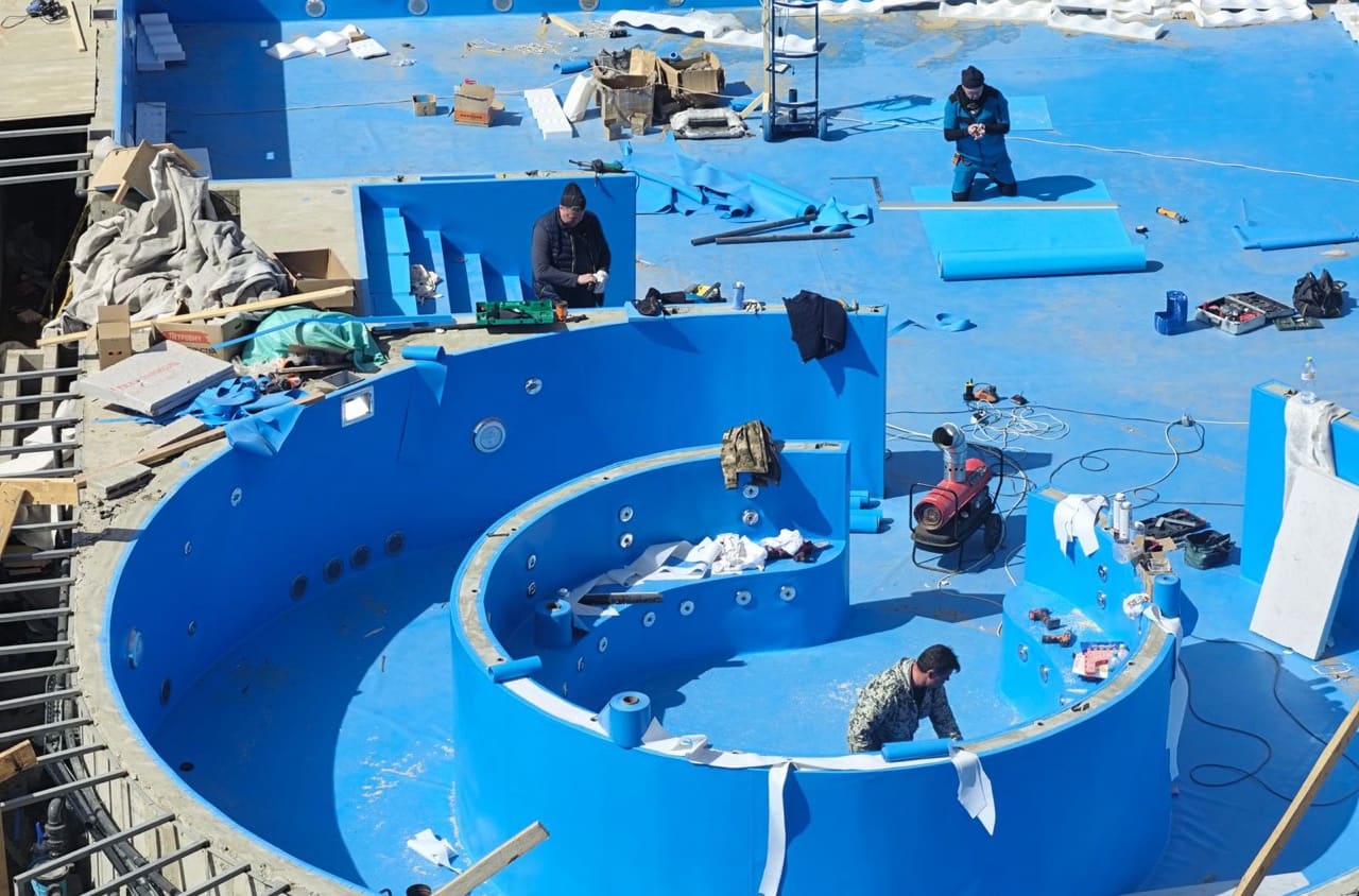 Arbeiter verkleiden ein neu gebautes Schwimmbecken im Garten