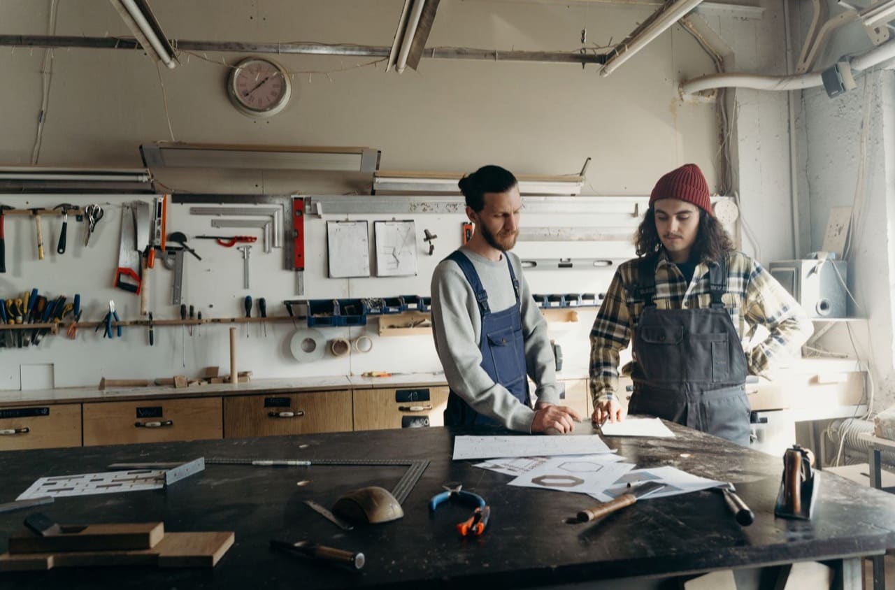Zwei Handwerker besprechen Pläne an der Werkbank