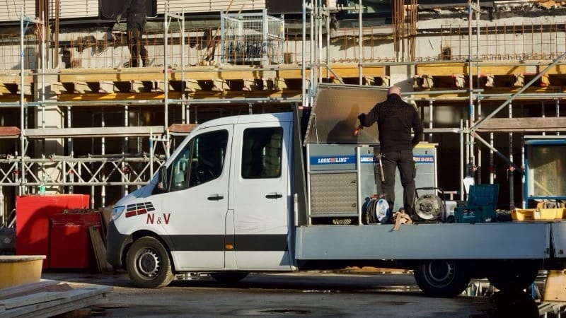 Handwerker mit Firmenfahrzeug auf der Baustelle